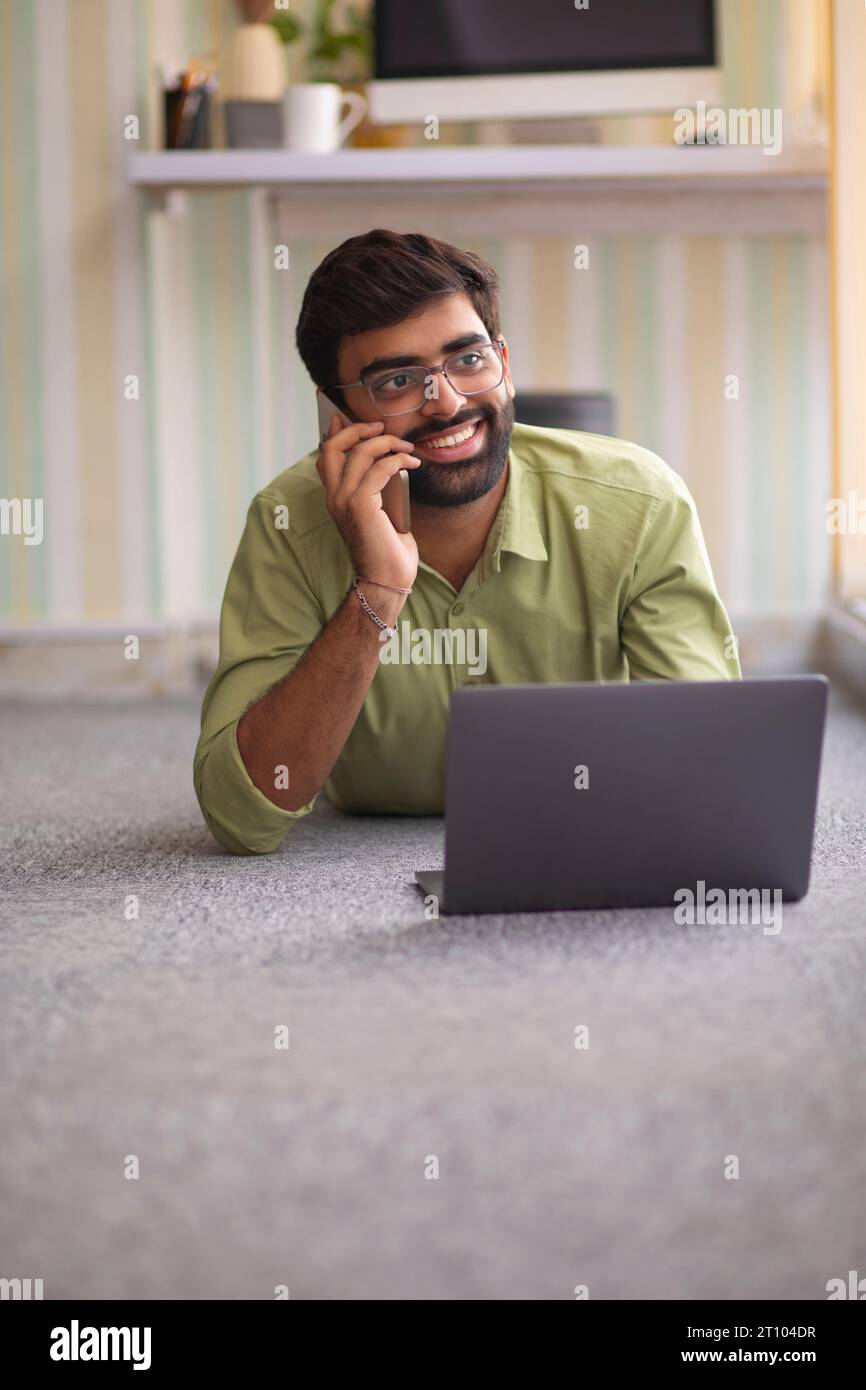 Junger Mann Gespräch am Handy mit Laptop Stockfoto