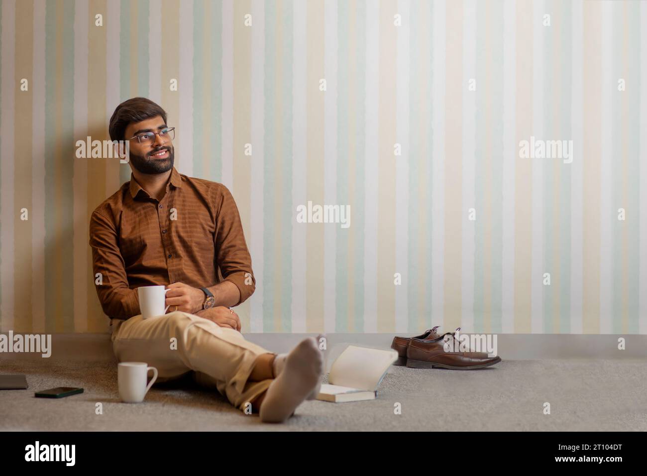 Junger Mann, der in seinem Heimbüro eine Kaffeepause macht Stockfoto