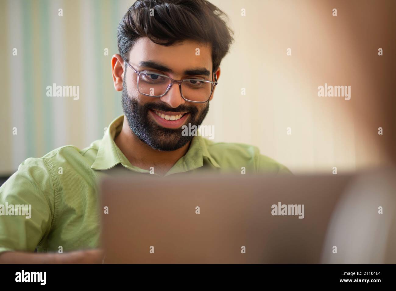 Nahporträt eines jungen Mannes, der im Heimbüro mit Laptop arbeitet Stockfoto