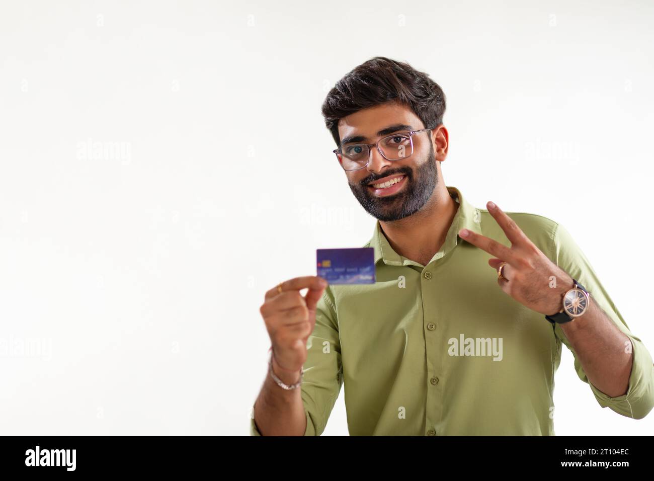 Porträt eines lächelnden jungen Mannes mit Kreditkarte vor weißem Hintergrund Stockfoto