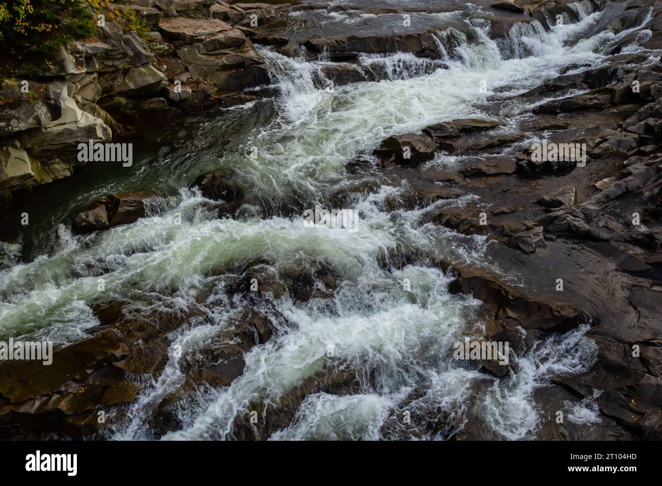 stromschnellen von Bergflüssen mit schnellem Wasser und großen felsigen Felsbrocken. Schneller Fluss eines Bergflusses im Frühling, Nahaufnahme. Stockfoto