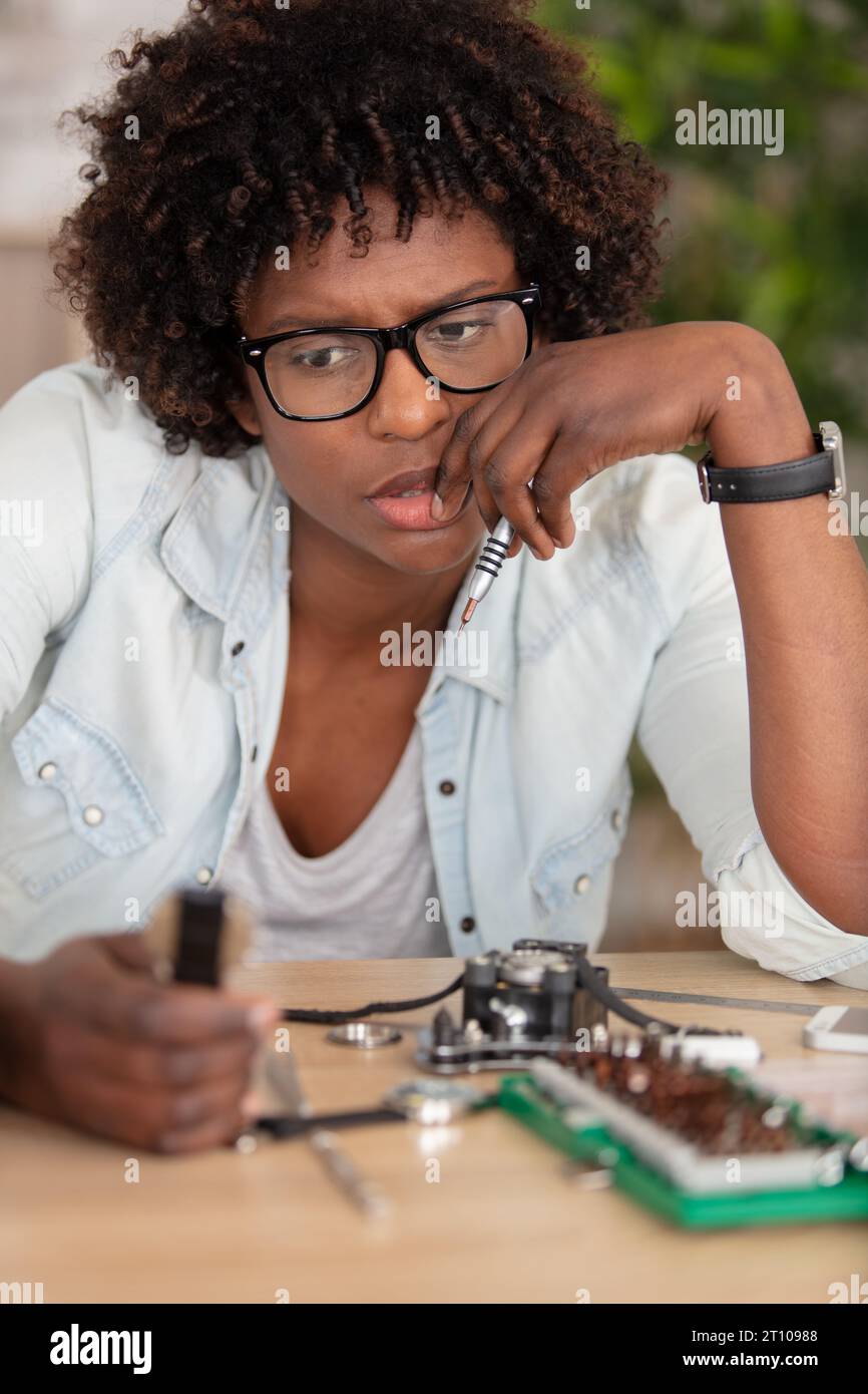 Eine denkende Technikerin repariert einen Computer in einem Raum Stockfoto