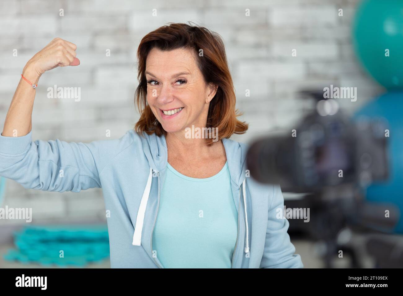Reife Frau beugt Armmuskel für Blog-Kamera Stockfoto