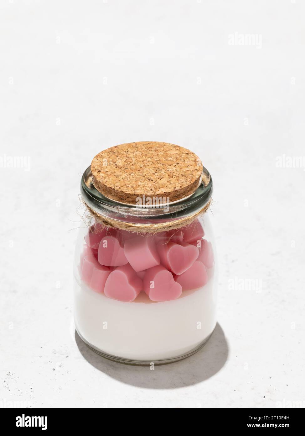 Duftende Kerze in einem transparenten Glasgefäß auf abstraktem Hintergrund mit Kopierraum Stockfoto