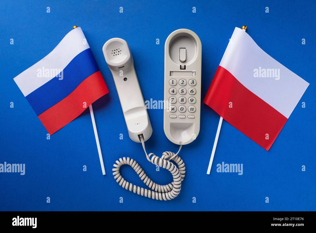 Altes Telefon und zwei Flaggen auf blauem Hintergrund, Konzept der Telefongespräche zwischen Polen und Russland Stockfoto