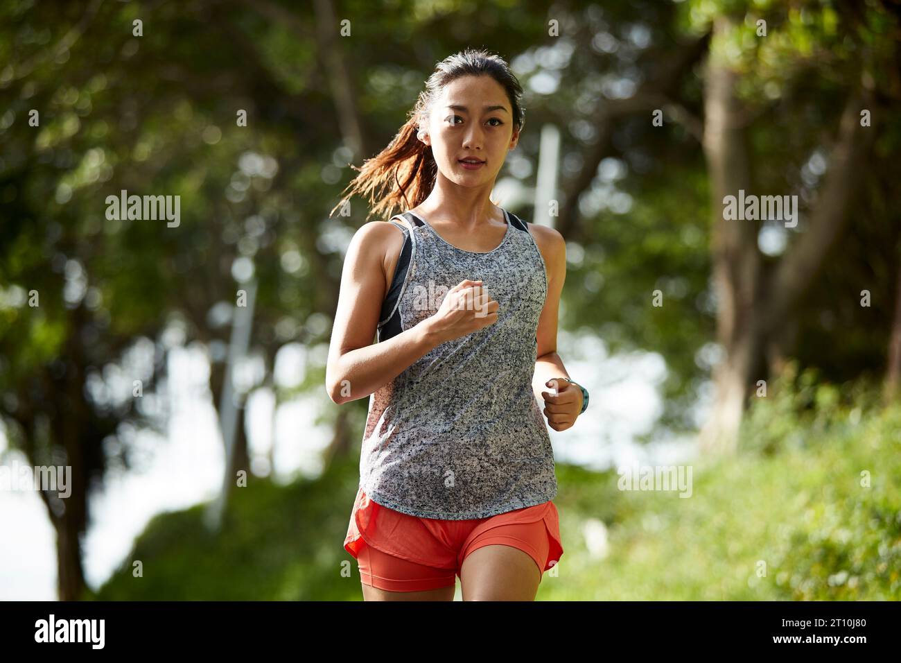 Junge asiatische Joggerin, die im Stadtpark im Freien trainiert Stockfoto