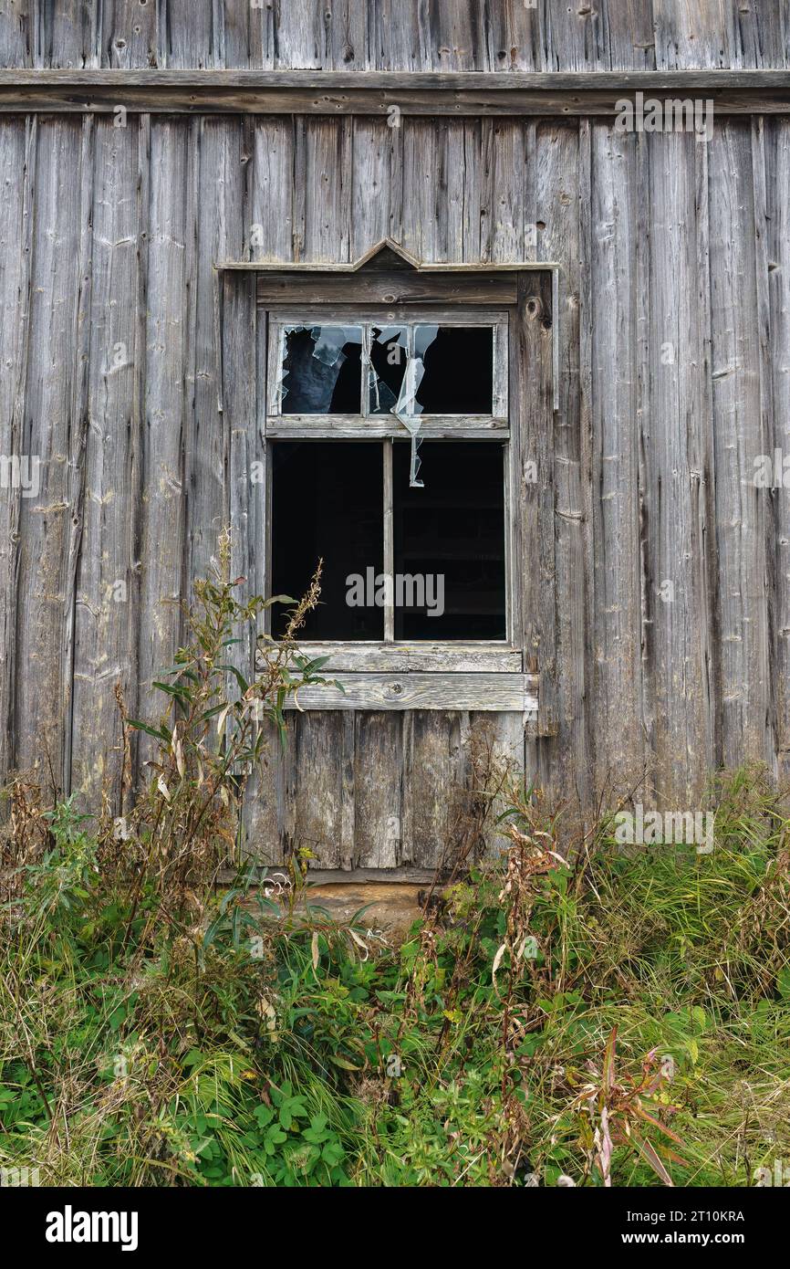 Kaputtes Fenster eines alten Holzgebäudes in der finnischen Landschaft. Stockfoto