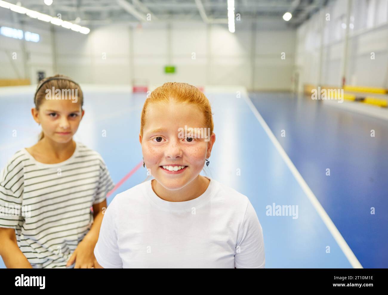 Porträt eines lächelnden Schulmädchens mit einer Freundin in der Turnhalle Stockfoto