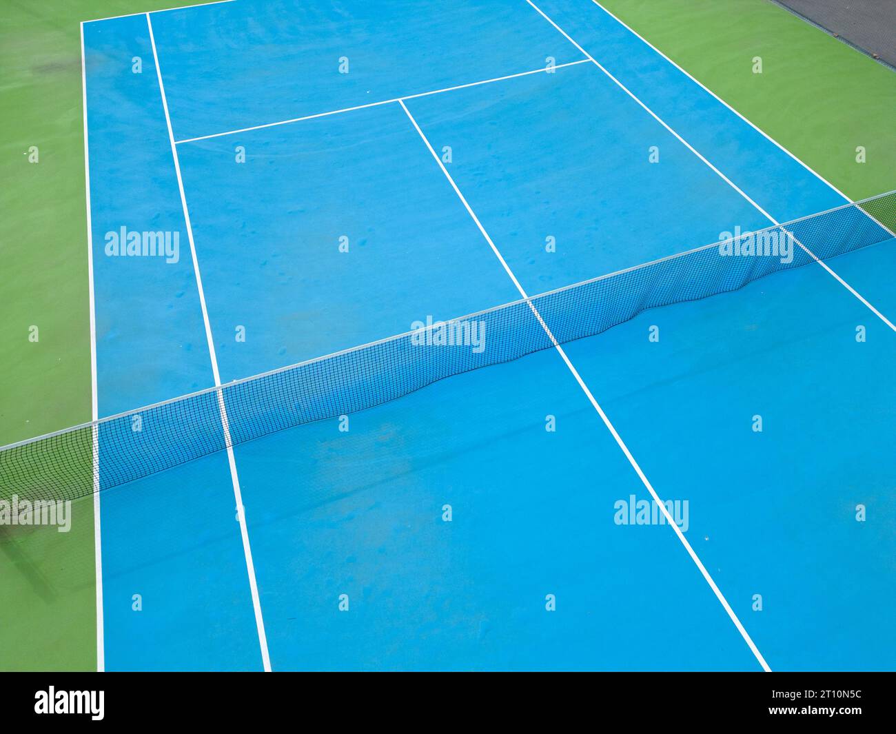 Aus der Vogelperspektive auf einen ruhigen blau-grünen Tennisplatz in einem leeren Zustand, der die gut gepflegte Oberfläche des Platzes und die Linien, die ihn markieren, hervorhebt Stockfoto