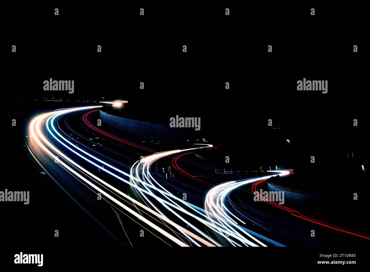 Geschwindigkeitsbewegung bei Nacht, befahrene Kreuzung mit leichten Fahrzeugen auf der Autobahn, Überführung der leichten Wege Stockfoto