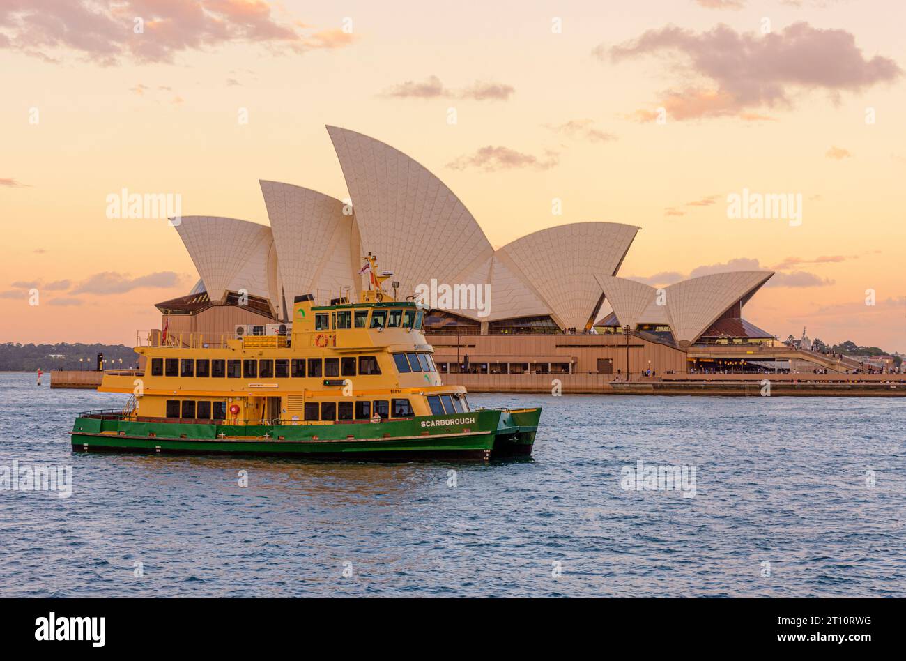 Das Opernhaus von Sydney bei Sonnenuntergang mit einer Fähre von Sydney, die am Hafen von Sydney vorbeifährt, Sydney, New South Wales, Australien Stockfoto