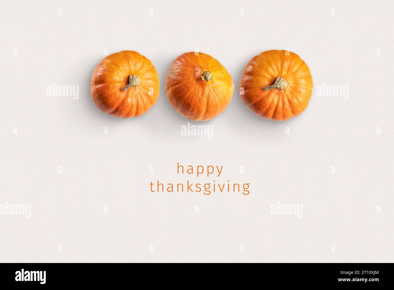 Thanksgiving-Karte: Drei Kürbisse auf Papier mit dem Text "Happy Thanksgiving" unten. Stockfoto