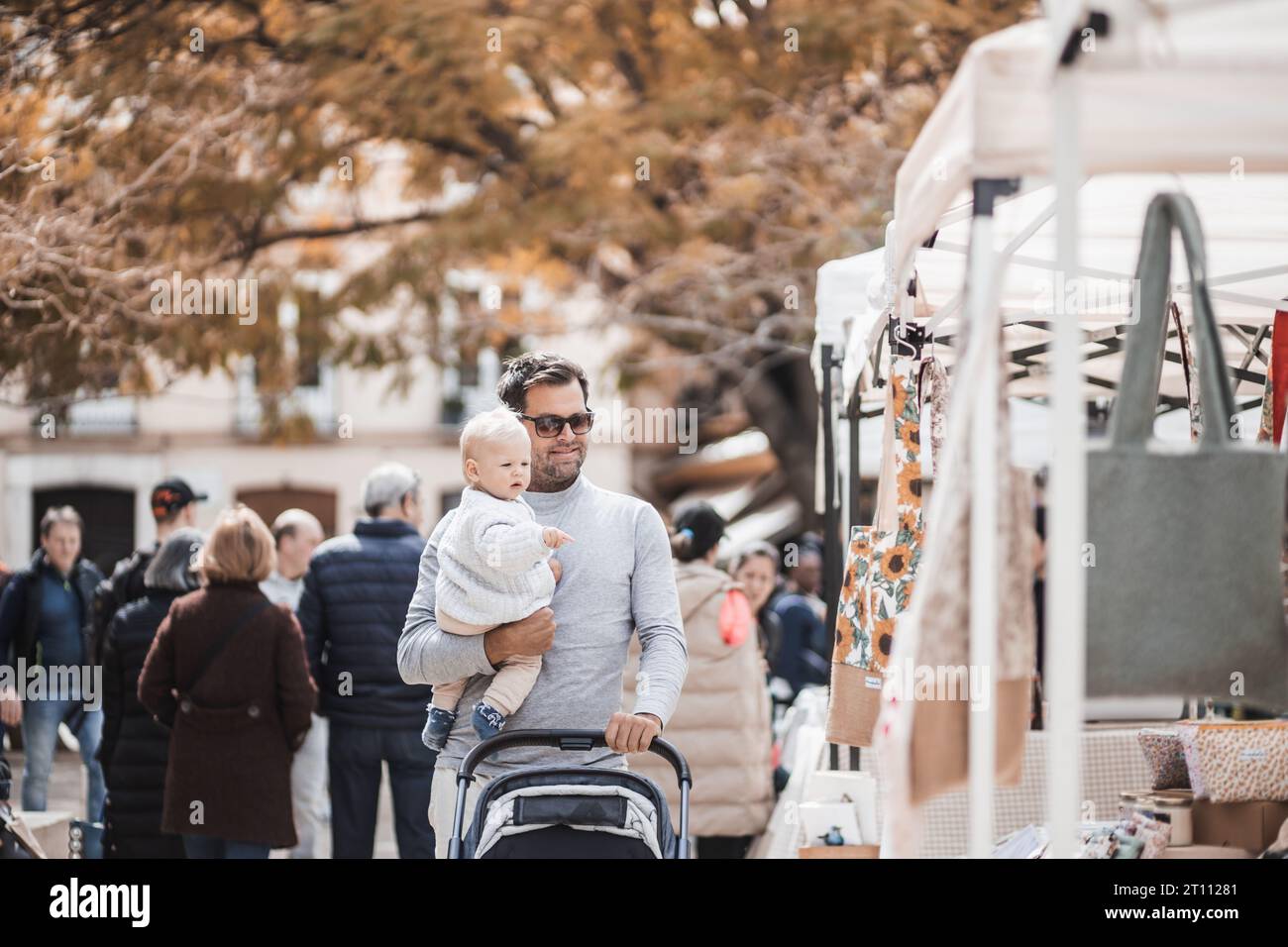 Vater läuft mit seinem kleinen Jungen und schiebt den Kinderwagen in einer Menge Leute, die den sonntagsflohmarkt in Malaga, Spanien, kennen lernen Stockfoto