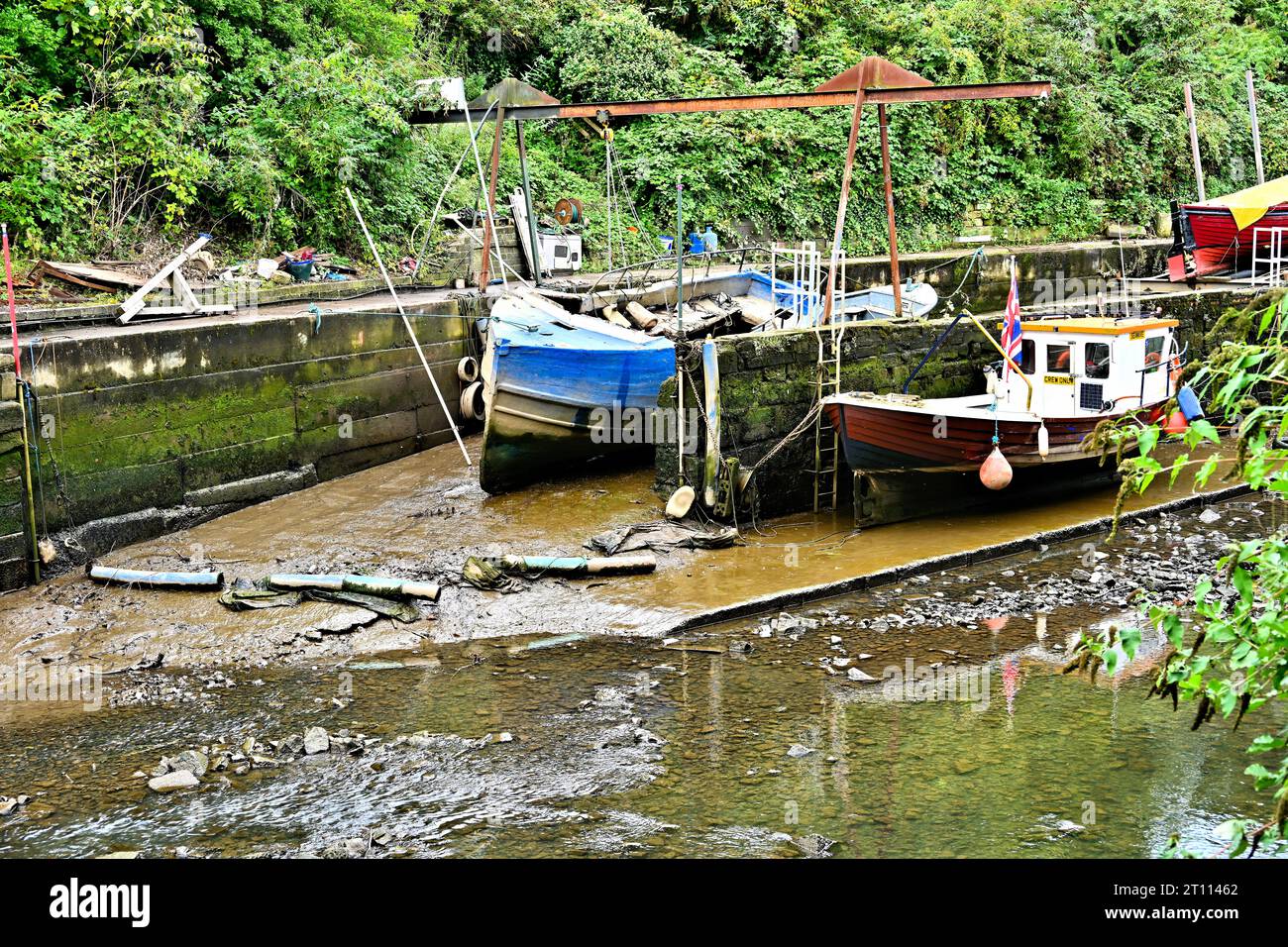 Kleine heruntergekommene Bootswerft inmitten des Schlammes und der Trümmer des Nebenflusses Ouseburn im Zentrum von Newcastle, während sie zum Fluss Tyne führt Stockfoto