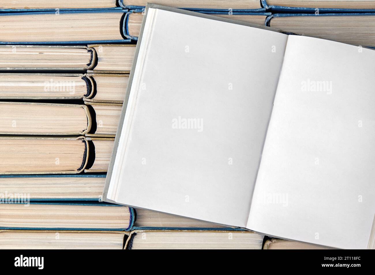 Ein offenes Buch mit leeren Seiten, ein Tagebuch auf einem Stapel schäbiger Bücher, die an ihren