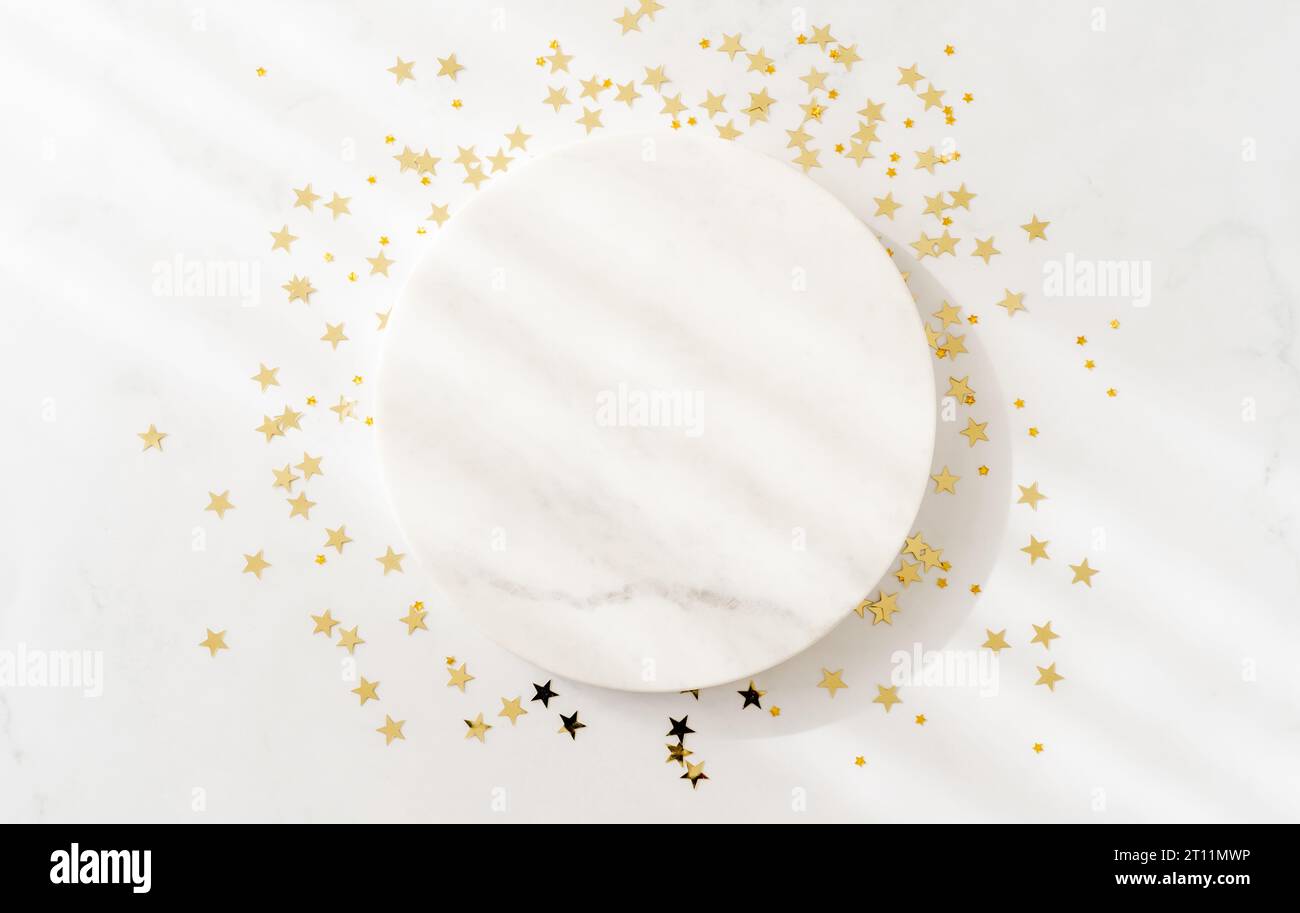 Weißes Marmor-Podium-Design und Konfetti mit goldenen Weihnachtssternen. Produktszene zur Präsentation von Kosmetik- oder Schönheitsprodukten Stockfoto