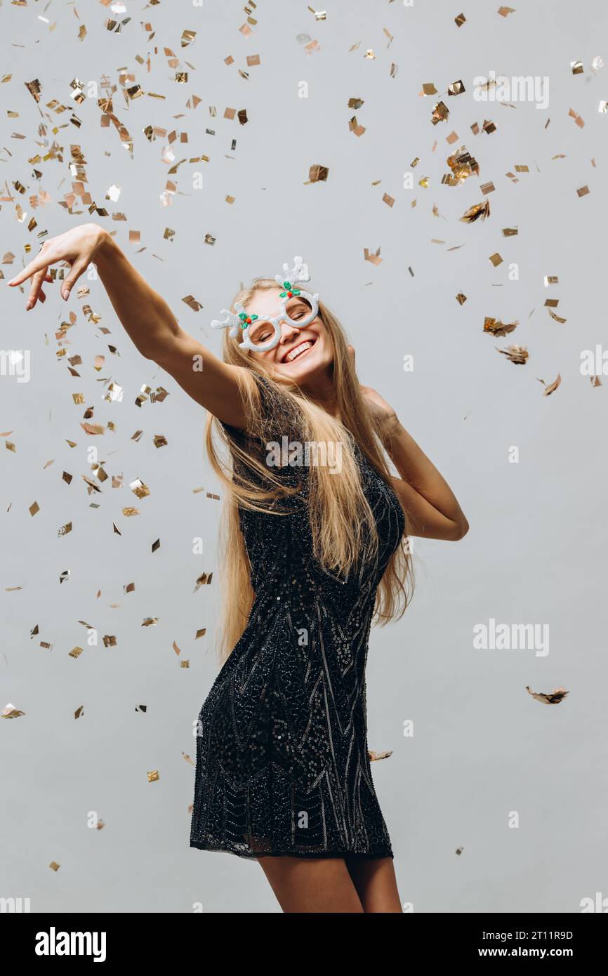 Neujahrsjunge Frau, die Spaß auf einer Weihnachtsfeier mit Konfetti hat Stockfoto