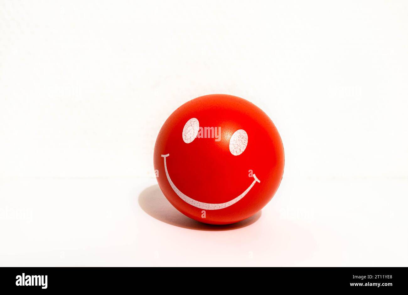 Roter Stressball mit Lächeln. Durch Drücken dieser Taste können die Menschen ihren Stress loswerden und sich entspannen. Stockfoto