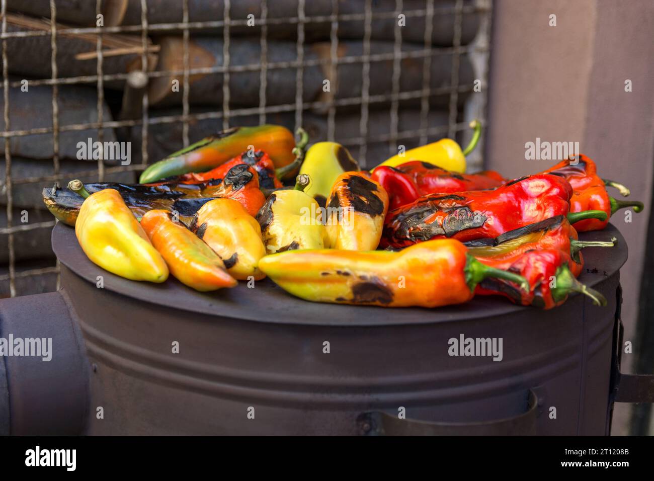 Nahaufnahme von gebratenen Paprika auf dem großen kreisrunden Brenner eines Holzofens im Hof an einem Herbsttag vor dem Haus Stockfoto
