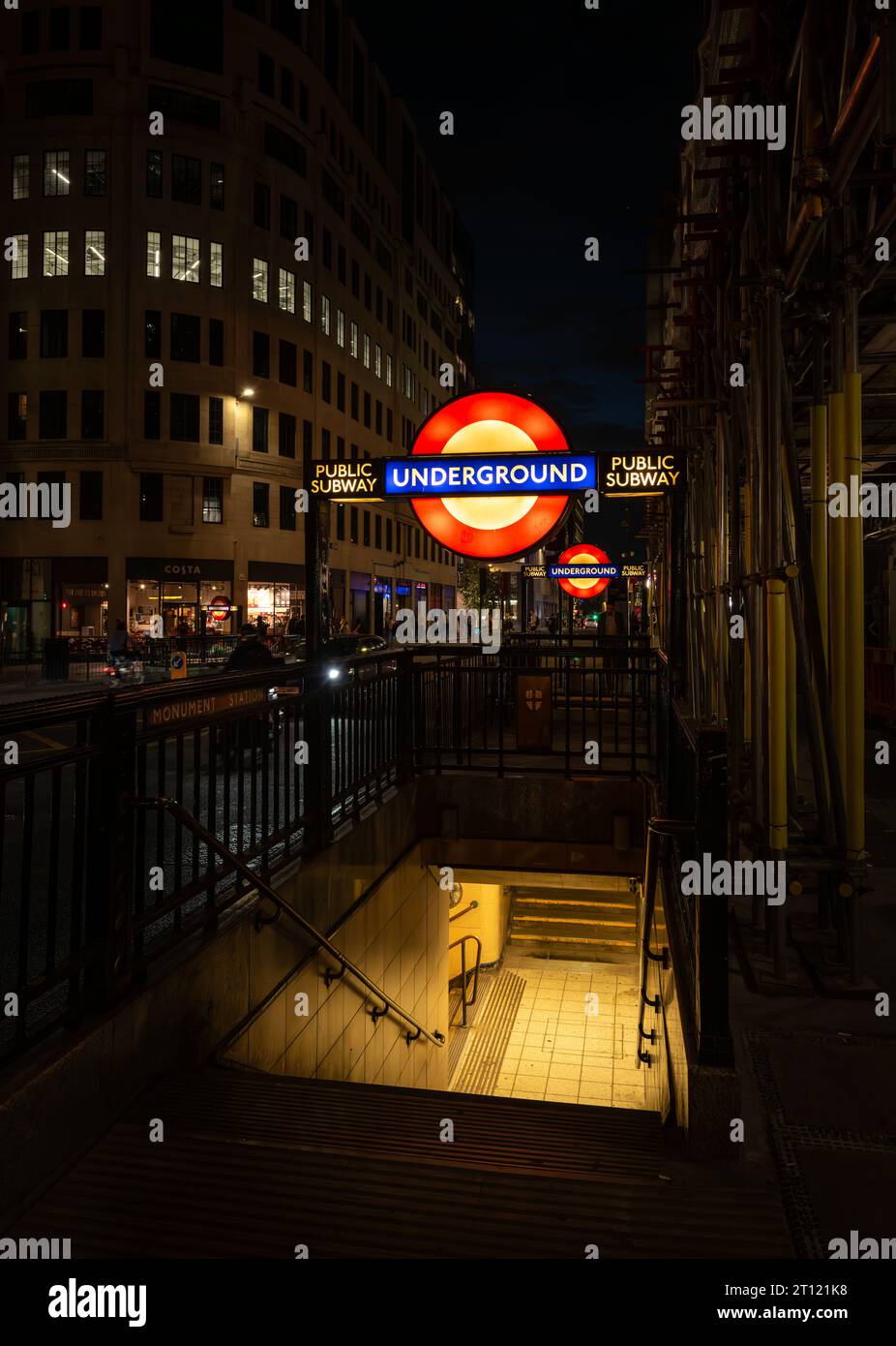 London, Großbritannien: Eintritt zur U-Bahn-Station Monument bei Nacht mit beleuchtetem U-Bahn-Schild. Stockfoto