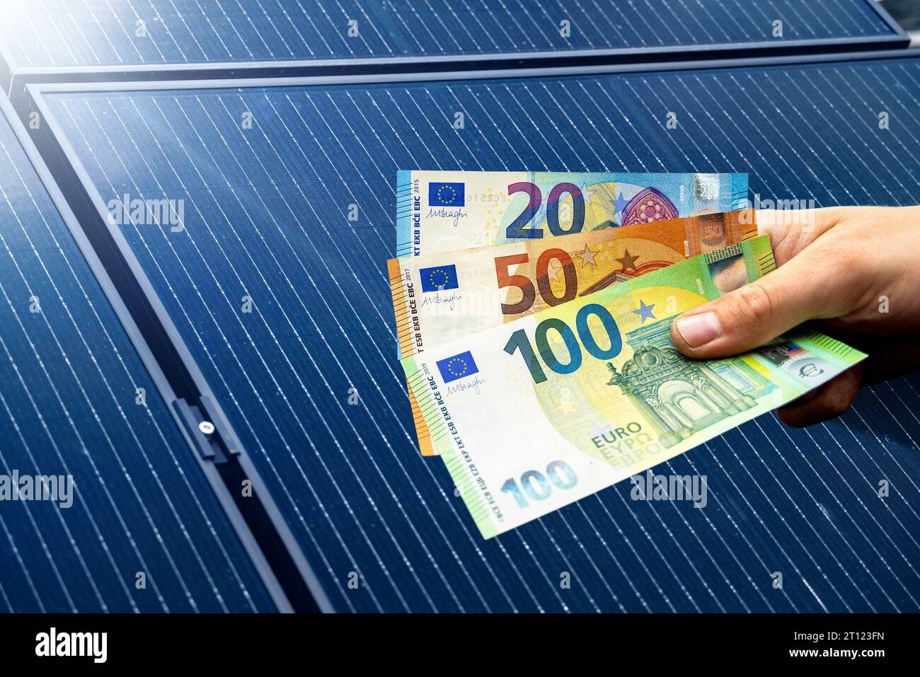 Euro-Scheine in der Hand gehalten, mit Solarpaneelen im Hintergrund Stockfoto
