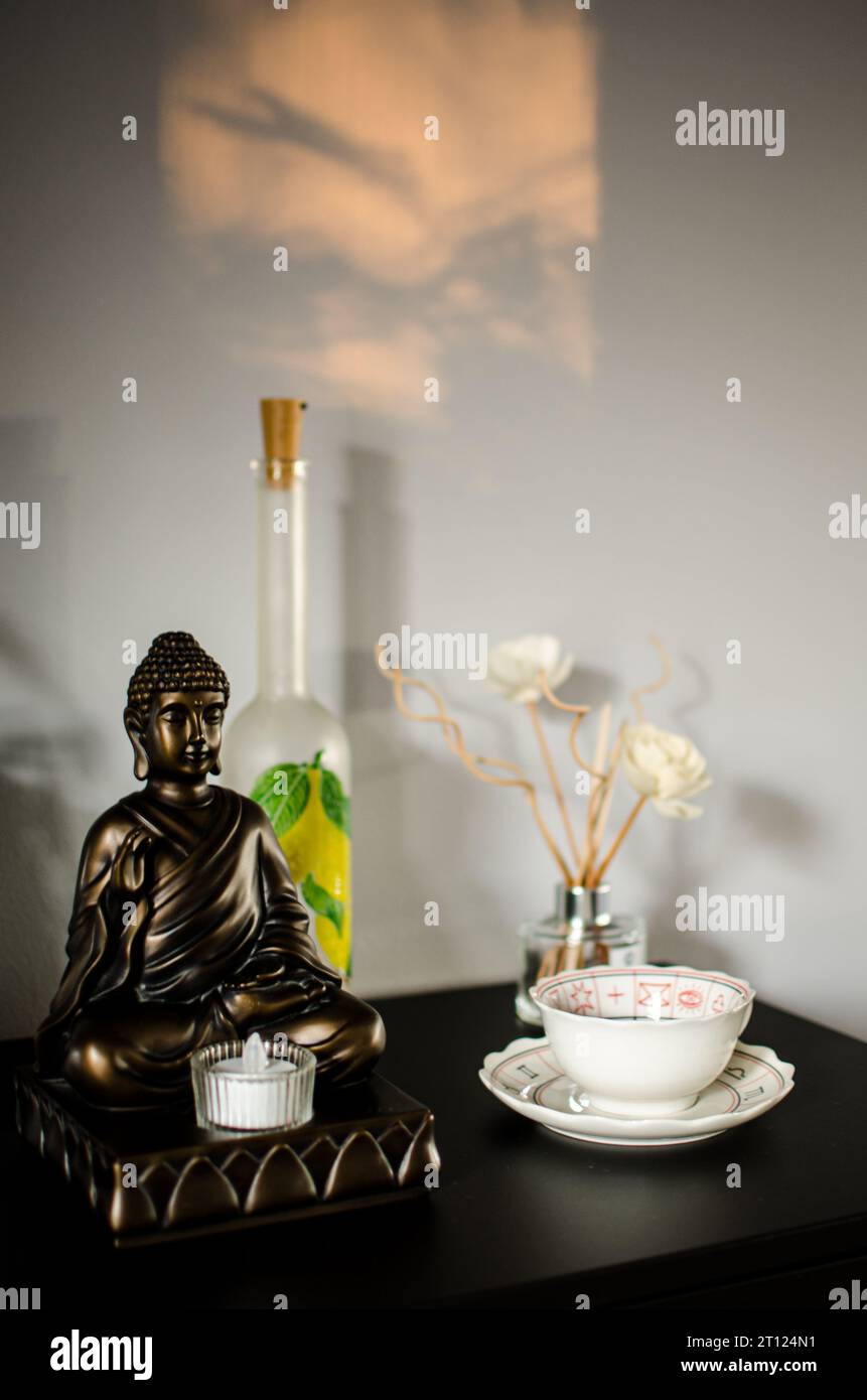 Buddha Kerzenständer mit Flasche und Schüssel auf einem Regal in einem Haus zur Dekoration Stockfoto
