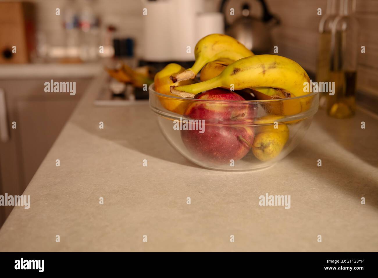 Bananen und Äpfel in einer Glasschale in der Küche Stockfoto
