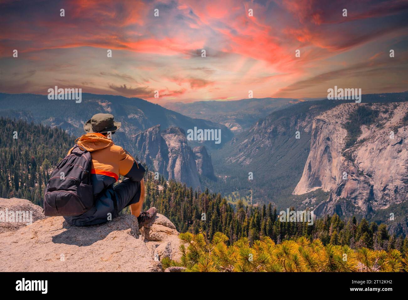 Ein junger Mann auf der Wanderung, der auf dem Aussichtspunkt Sentinel Dome im Yosemite-Nationalpark sitzt und den El Capitan Mountain betrachtet. Usa Stockfoto