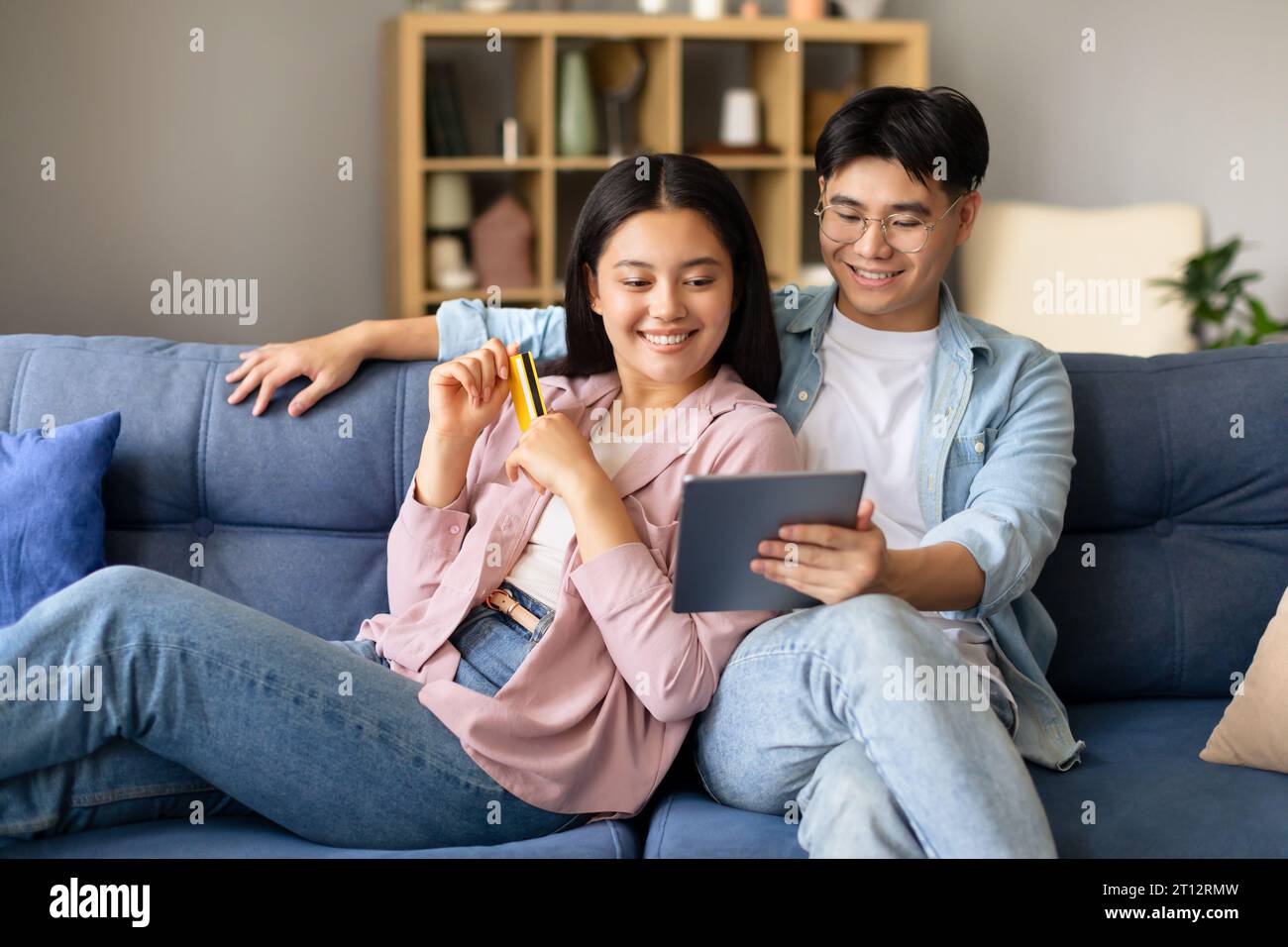 Koreanischer Mann und koreanische Frau, die über Tablet-Indoor einkaufen Stockfoto