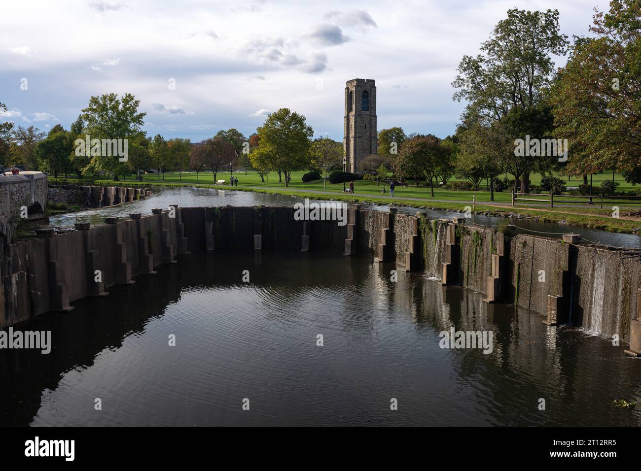Die ruhige Szene in Frederick, MD: Der Carroll Creek Damm, der berühmte Carillon Tower und eine riesige grüne Rasenfläche bieten einen ruhigen, urbanen Rückzugsort im Baker Park. Stockfoto