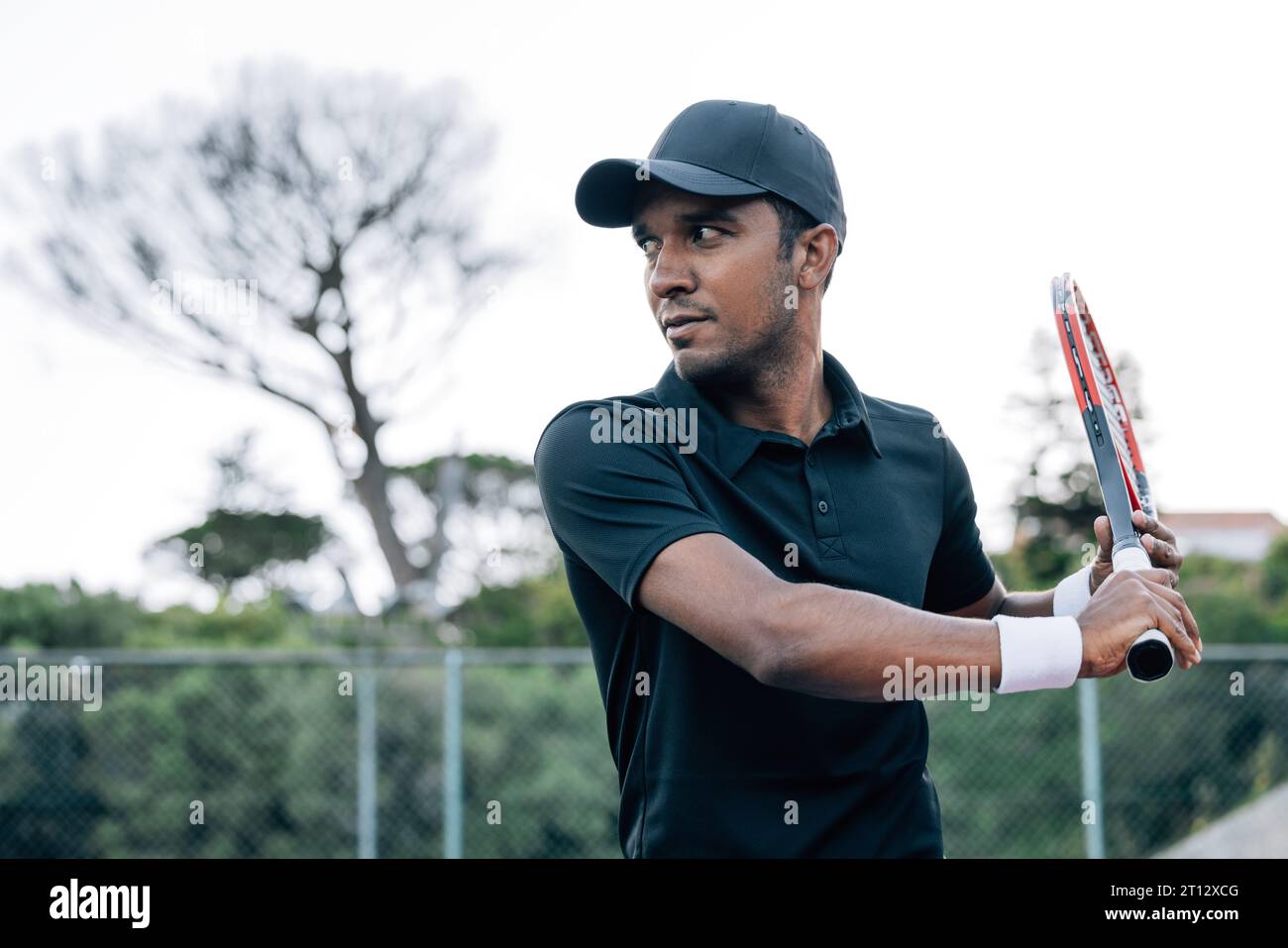 Porträt eines selbstbewussten Tennisspielers in einer Kappe, die Schläger hält Stockfoto