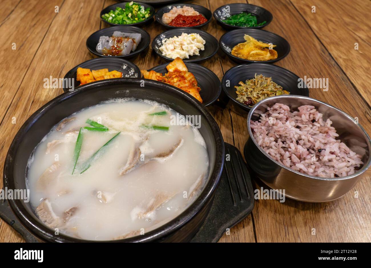 Dwaeji Gukbap, ein beliebtes koreanisches Reisgericht mit Schweinefleisch, serviert mit traditionellen Beilagen aus Kimchee, eingelegtem Rettich, gebratenen Sardellen, Konjac, Stockfoto
