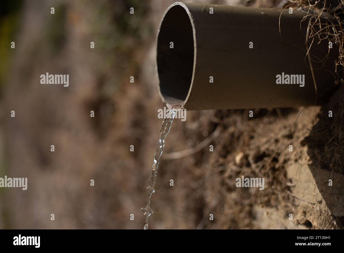 Eine Nahaufnahme eines Rohrs mit Wasser, das aus ihm austritt, Schlucht, braun, Stockfoto