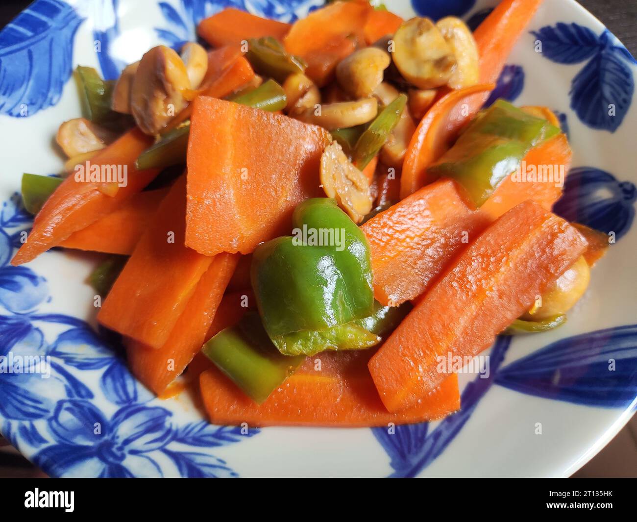 Karottenscheibe mit Fleisch und grünem Pfeffer auf der weißen Platte Stockfoto