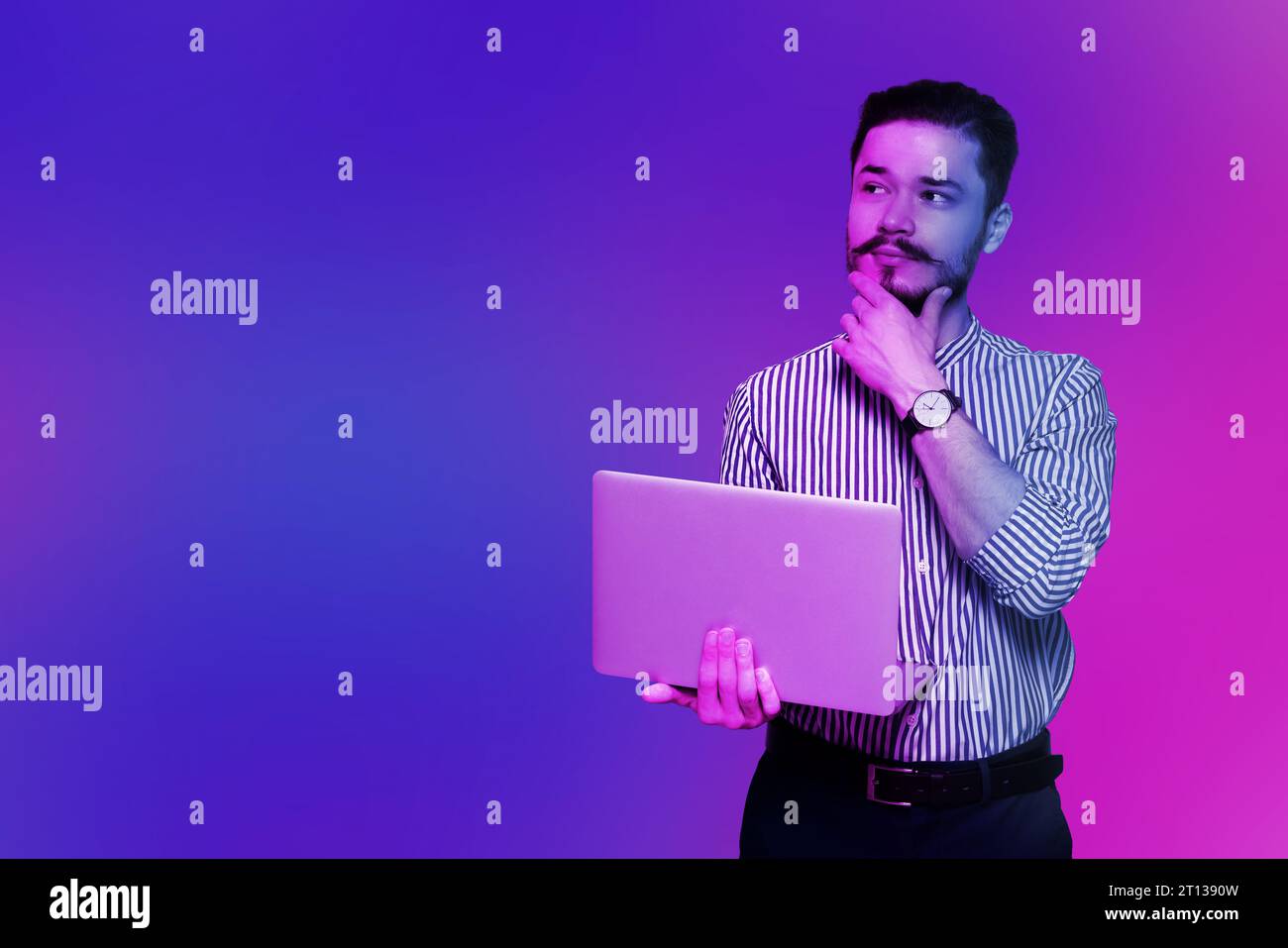 Schöner Mann mit Laptop in Neonlichtern, Platz für Text Stockfoto