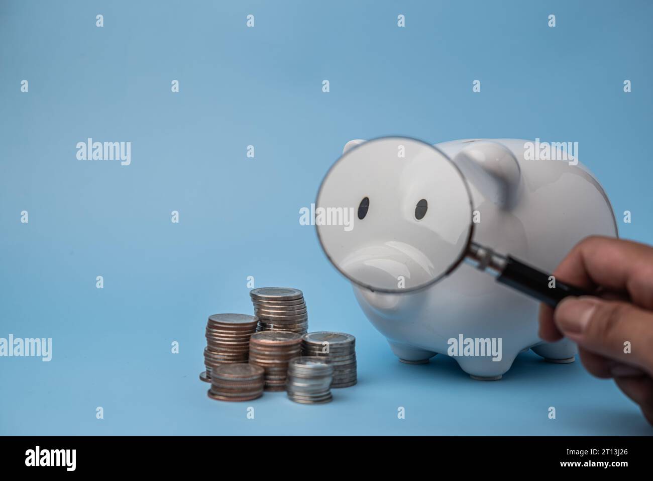 Geld sparen mit einer Sparkasse und einem Vergrößerungsglas. Finanzieller Wohlstand der Unternehmen und Anhäufung von Wohlstand Stockfoto