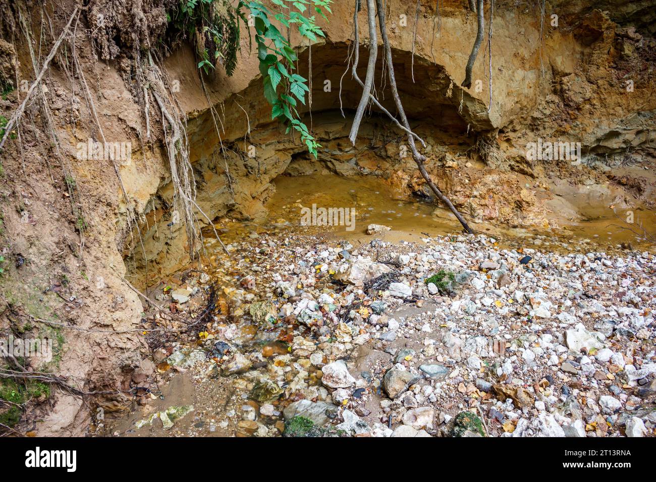 Der Wasserfluss erodiert die Sandschicht am Ufer Stockfoto