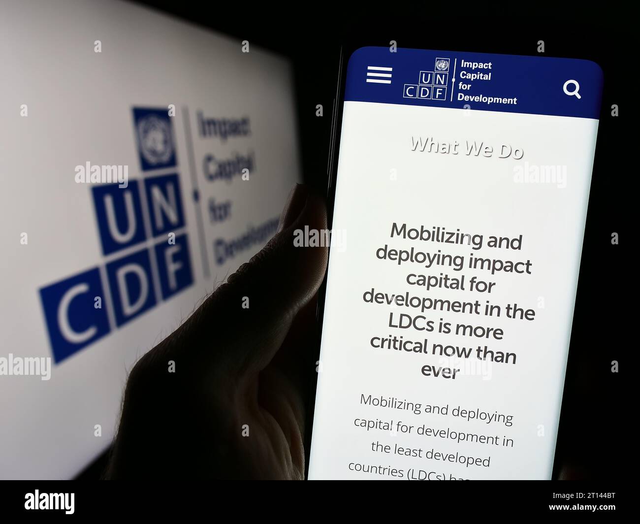 Person, die ein Mobiltelefon hält, mit Website des Fonds der Vereinten Nationen für Kapitalentwicklung (UNCDF) vor dem Logo. Konzentrieren Sie sich auf die Mitte des Telefondisplays. Stockfoto