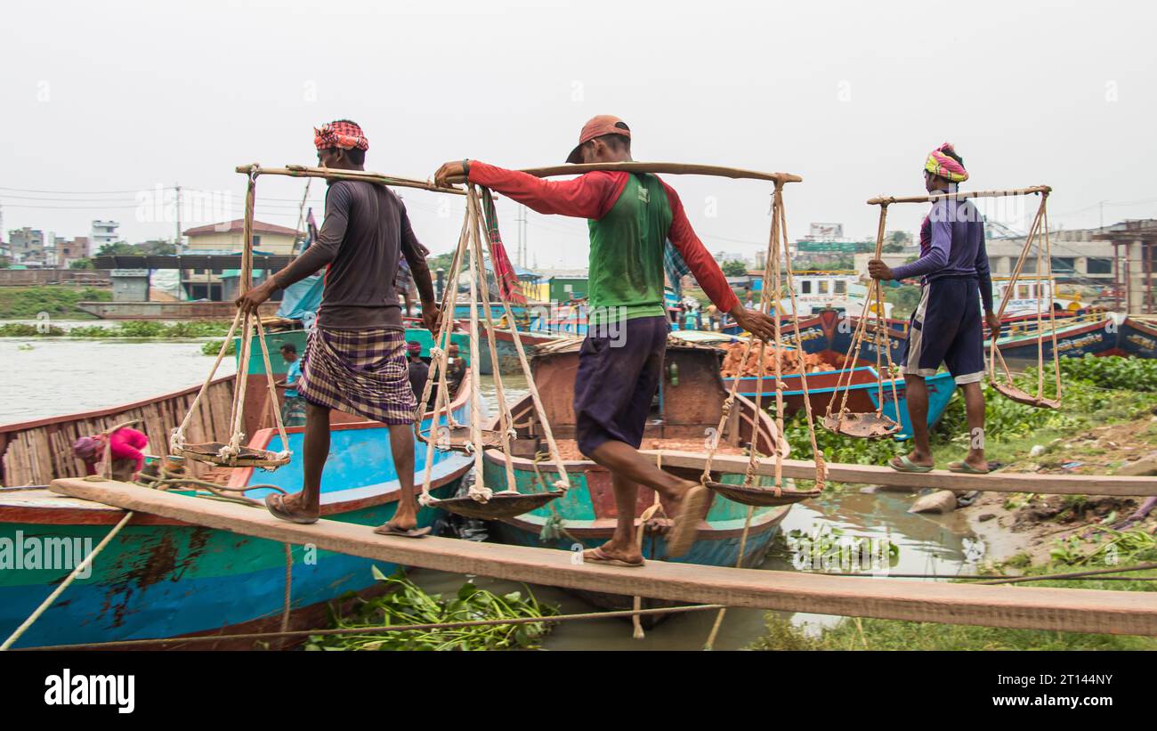 Menschen, die Ziegelsteine vom Boot abladen, das Bild, das am 29. Mai 2022 aufgenommen wurde, aus Amen Bazar, Bangladesch, wo Arbeiter schwere Ziegelsteine abladen Stockfoto