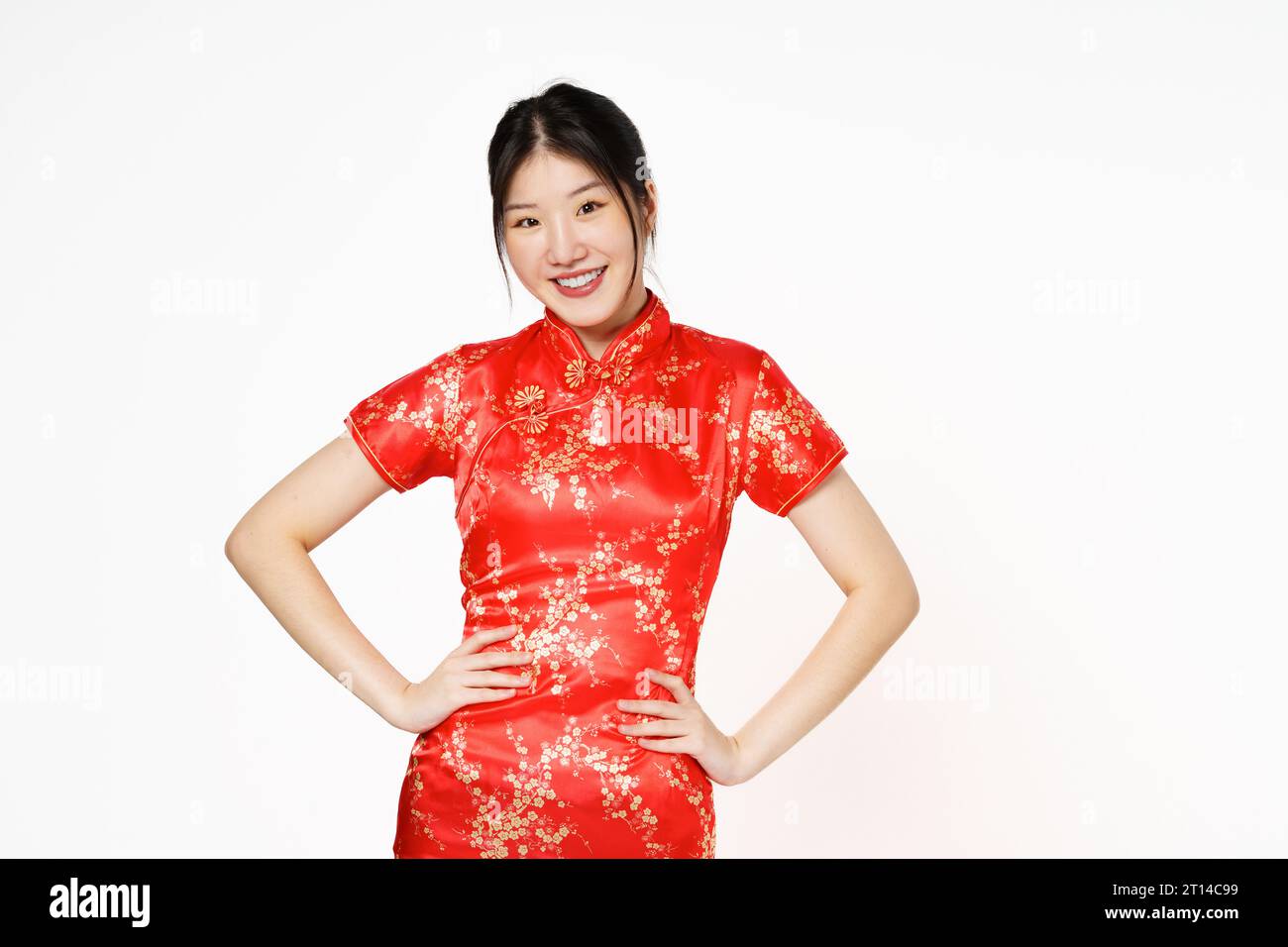 Asiatische Frau trägt traditionelles Cheongsam Qipao Kleid, stehend mit Händen auf der Taille und Blick auf die Kamera isoliert auf weißem Hintergrund. Glückliches Chinesisch ne Stockfoto