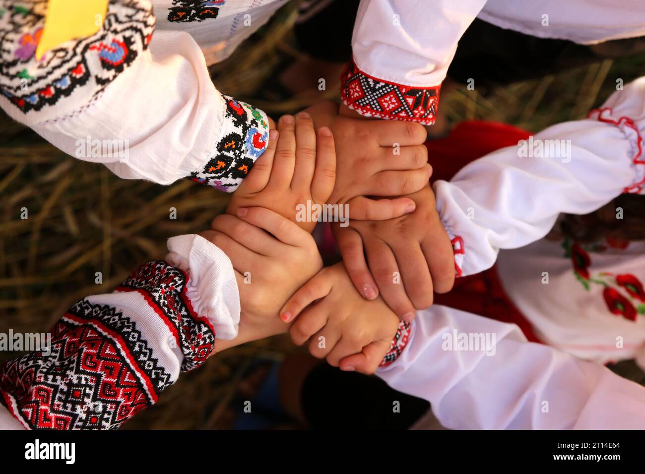 Die Hände von Kindern in bestickten Hemden sind in einer einladenden Geste verflochten. Die vereinigten Hände symbolisieren Einheit. Unabhängigkeitstag der Ukraine, Con Stockfoto