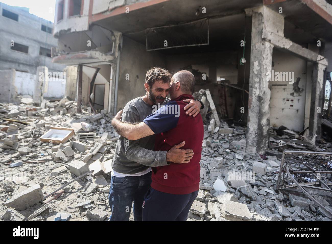 Gaza-Stadt, Palästinensische Gebiete. Oktober 2023. Palästinensische Männer trösten sich gegenseitig bei der Inspektion des zerstörten Viertels Karama nach einem israelischen Bombenanschlag in Gaza-Stadt. Quelle: Mohammed Talatene/dpa/Alamy Live News Stockfoto