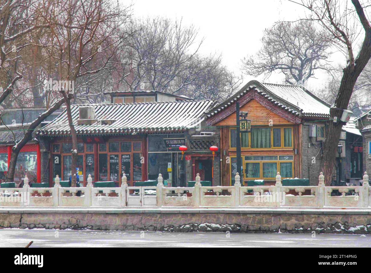 Erkunden Sie das bezaubernde Spektakel der vielfarbigen traditionellen Häuser, eingebettet in ein winterliches Wunderland unter einer unberührten chinesischen Schneelandschaft Stockfoto
