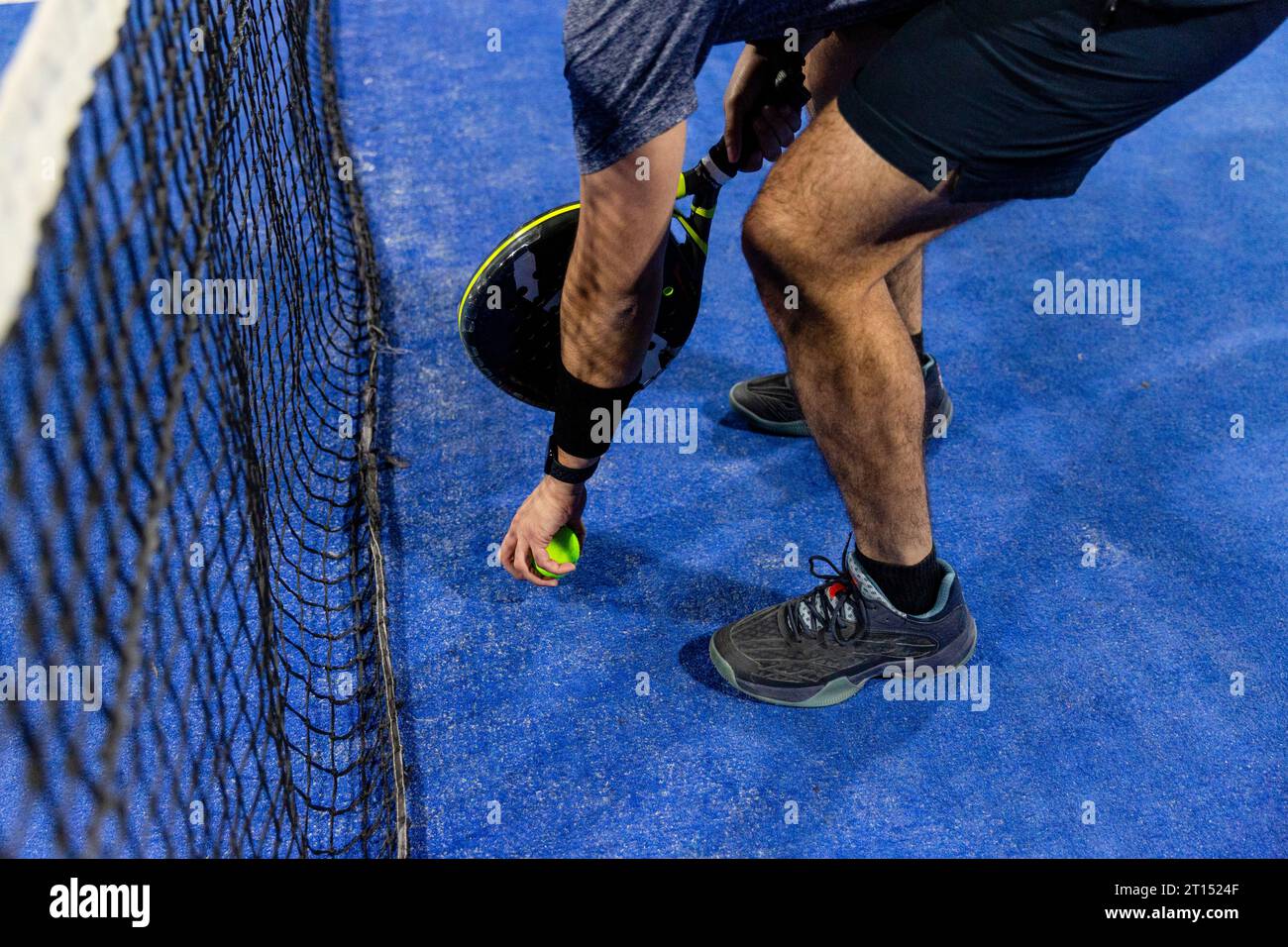 Ein Mann spielt ein Padel-Spiel auf einem blauen Hof mit seinem Schläger Stockfoto