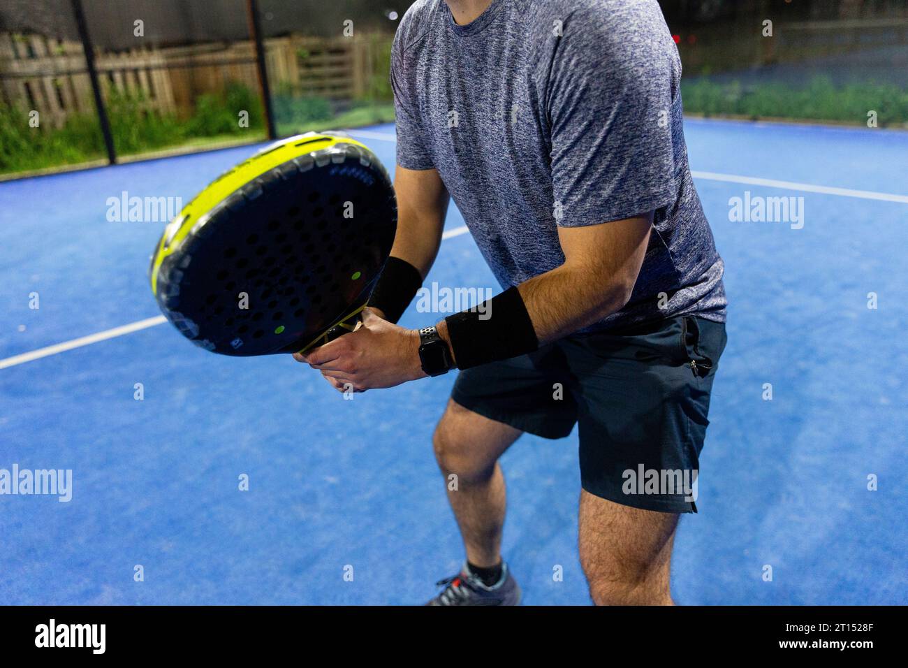 Ein Mann spielt ein Padel-Spiel auf einem blauen Hof mit seinem Schläger Stockfoto
