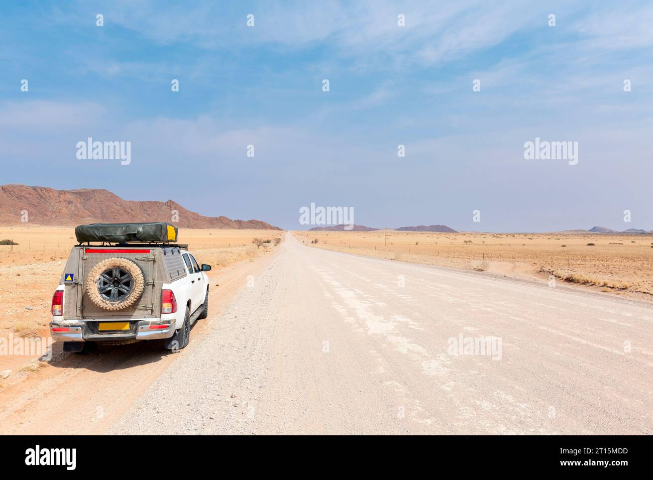 Pickup Truck fährt auf einer langen, geraden Wüstenstraße in Richtung Berge. Stockfoto