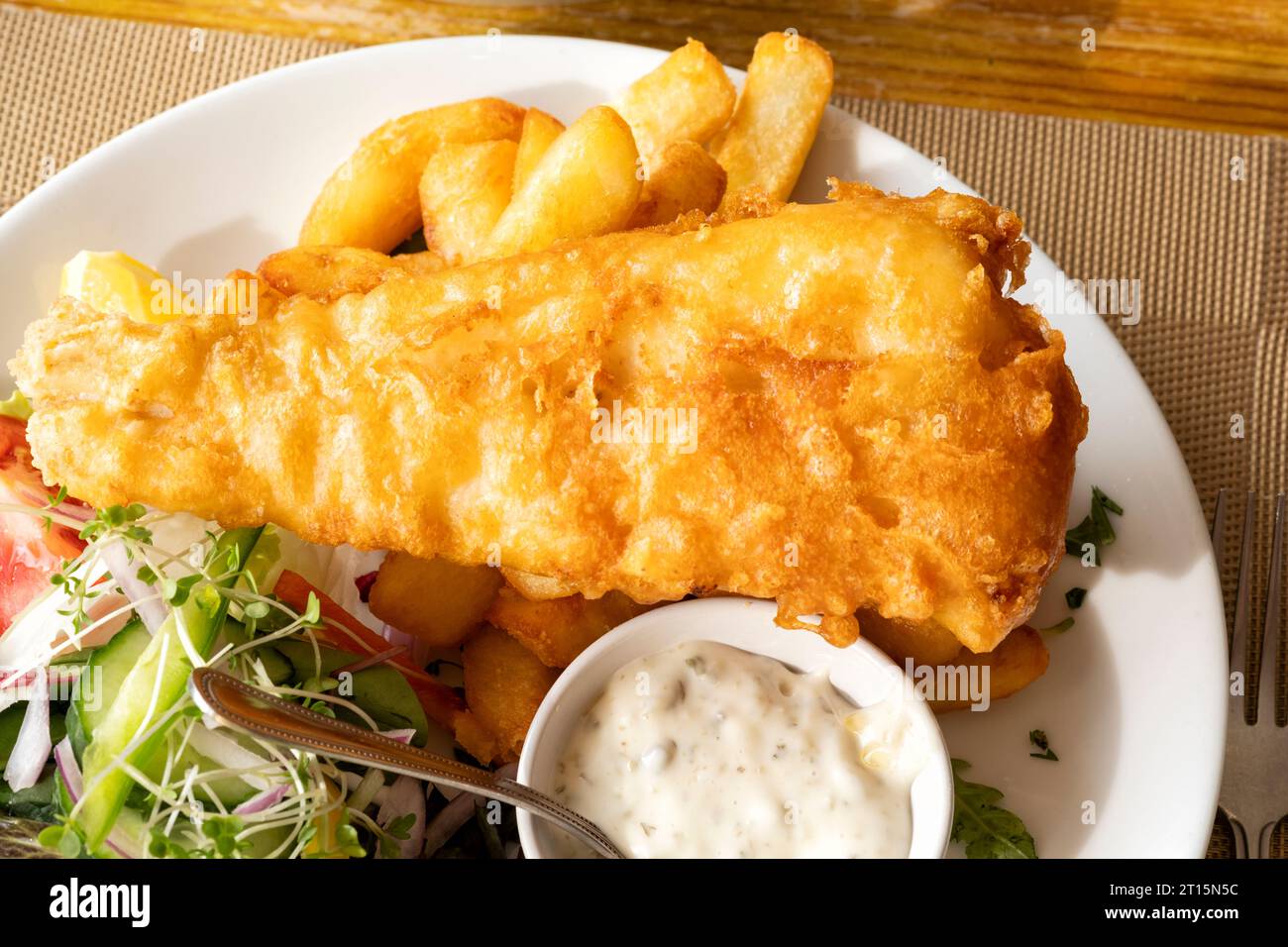 Eine traditionelle englische Fish and Chip Mahlzeit, serviert auf einem Tisch in einem Fish and Chip Restaurant. Die Teller enthalten frisch zerlegte Co und Chips Stockfoto