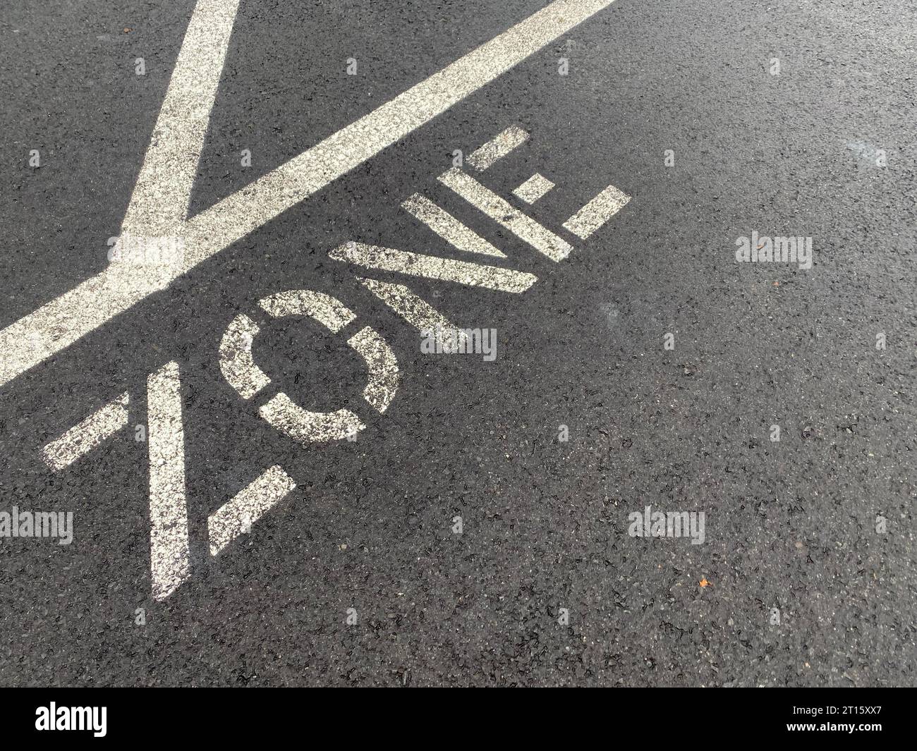 Weiße Linien und „ZONE“ auf dem Asphalt des städtischen Parkplatzes. Verkehr und Parken sind mit weißen Linien und „ZONE“ auf dem städtischen Parkgelände verbunden. Verkehrs- und Parkkonzept. Stockfoto