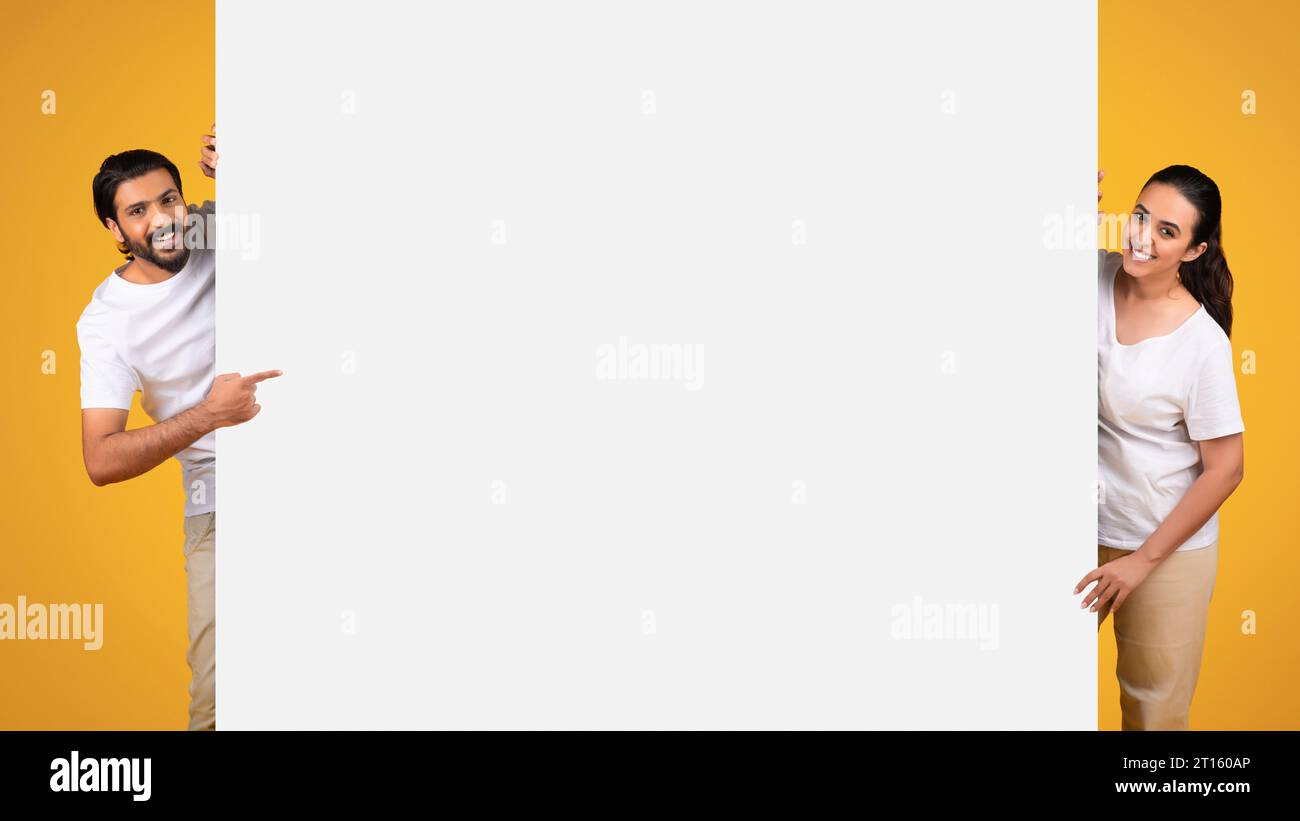 Ein Paar, das auf ein Banner mit leerem Platz und gelbem Hintergrund zeigt Stockfoto