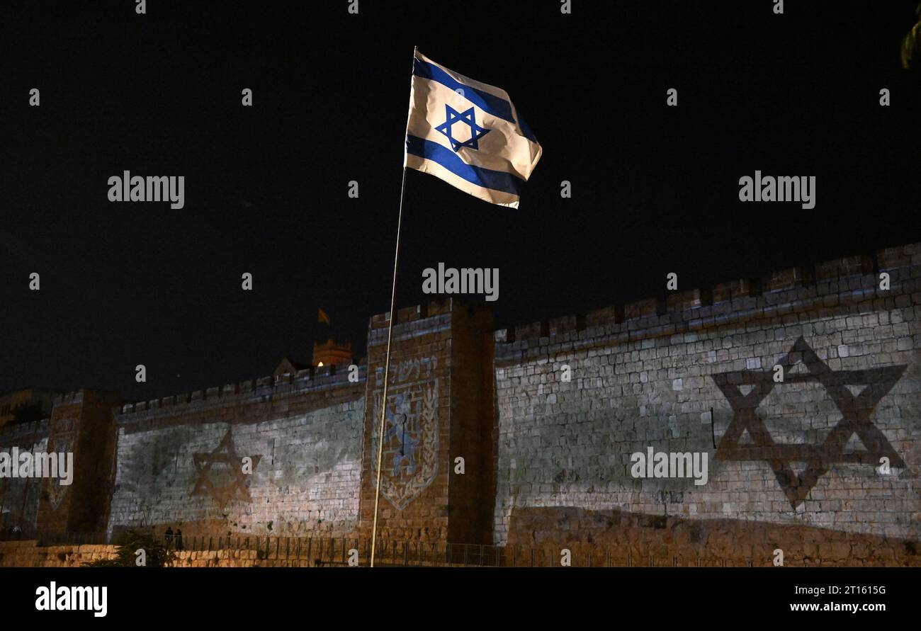 Die Altstadt Von Jerusalem, Israel. Oktober 2023. Eine israelische Flagge fliegt in der Nähe von projizierten Fahnen an der Mauer der Altstadt von Jerusalem, nachdem Israel am Mittwoch, den 11. Oktober 2023, einen massiven Terroranschlag der Hamas an der Grenze zu Gaza erlitten hatte. Foto: Debbie Hill/ Credit: UPI/Alamy Live News Stockfoto